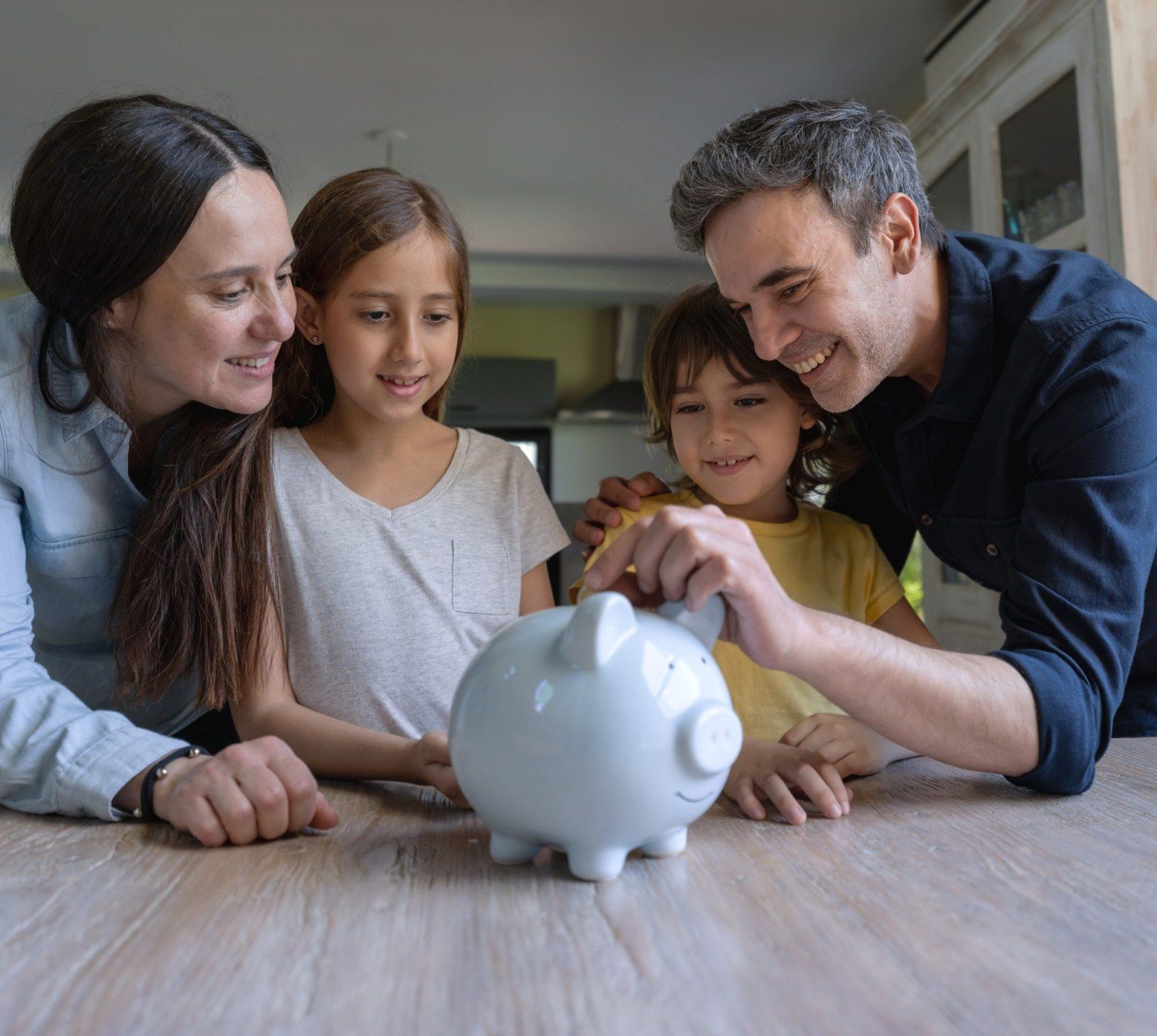 Parents and kids putting money in piggy bank