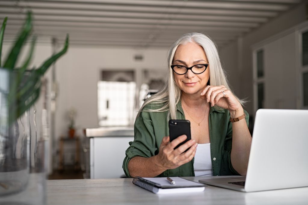A woman smiling while looking at her phone in her kitchen