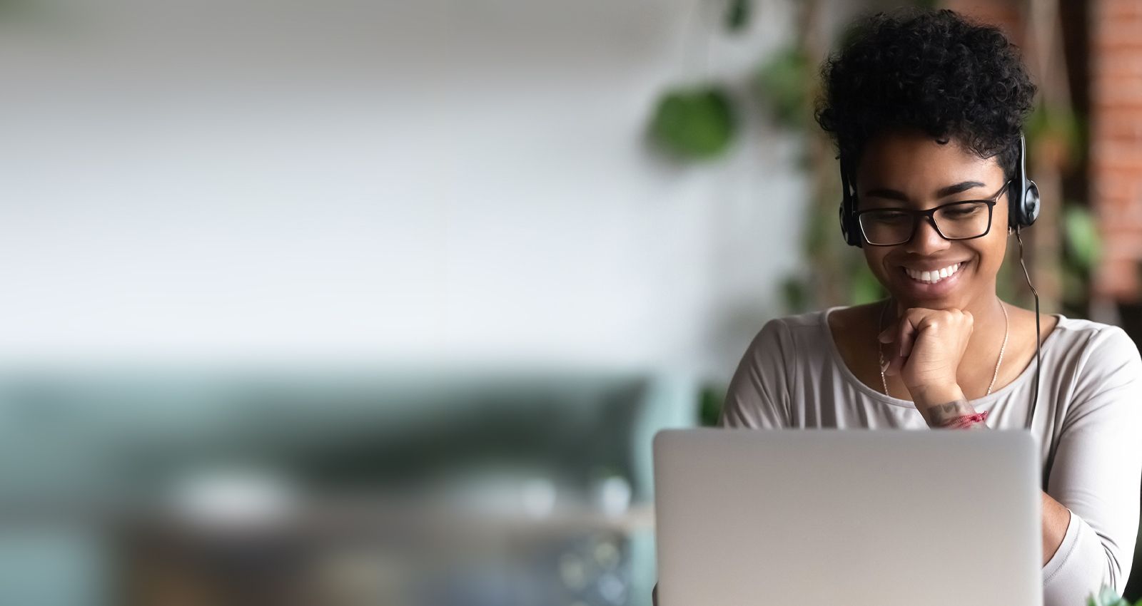 Woman wearing headphones while looking at her laptop