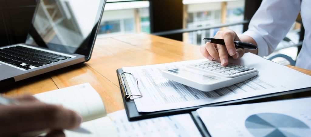 A woman at a desk using a calculator on top of documents