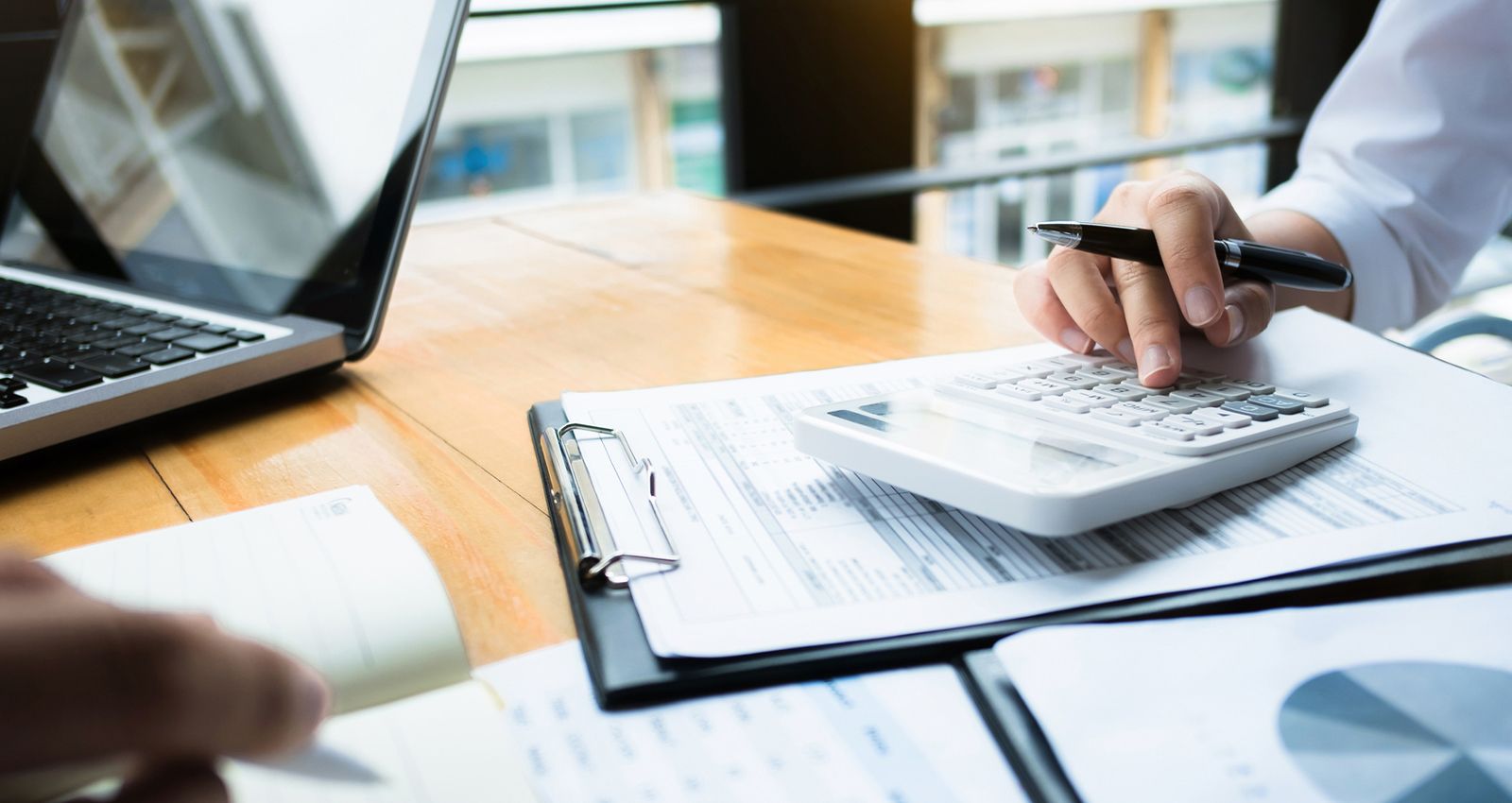 A woman at a desk using a calculator on top of documents