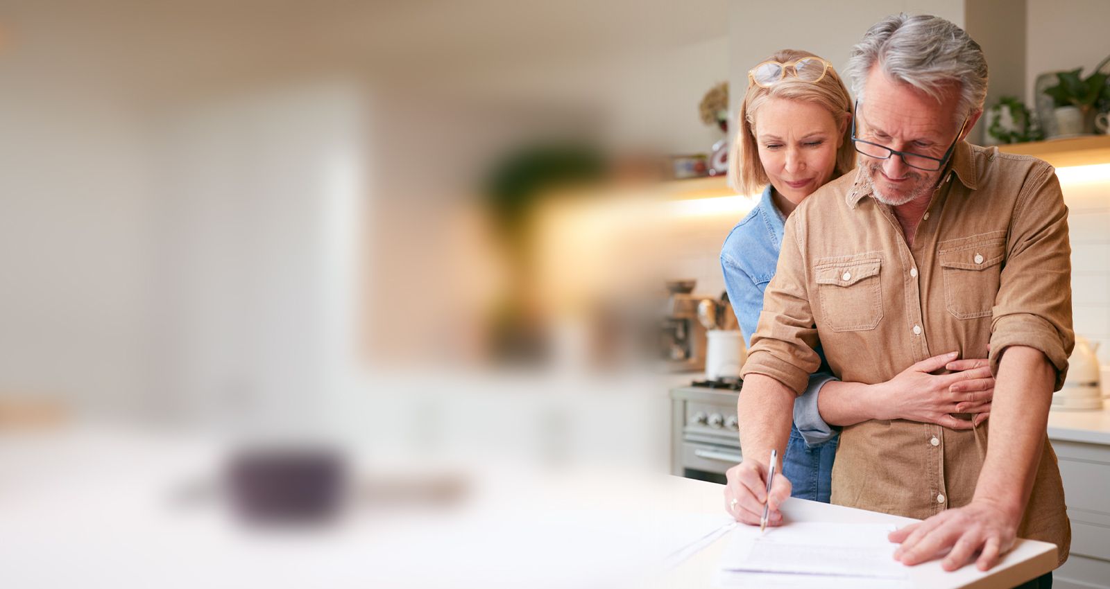 Middle-aged couple signing documents in the kitchen