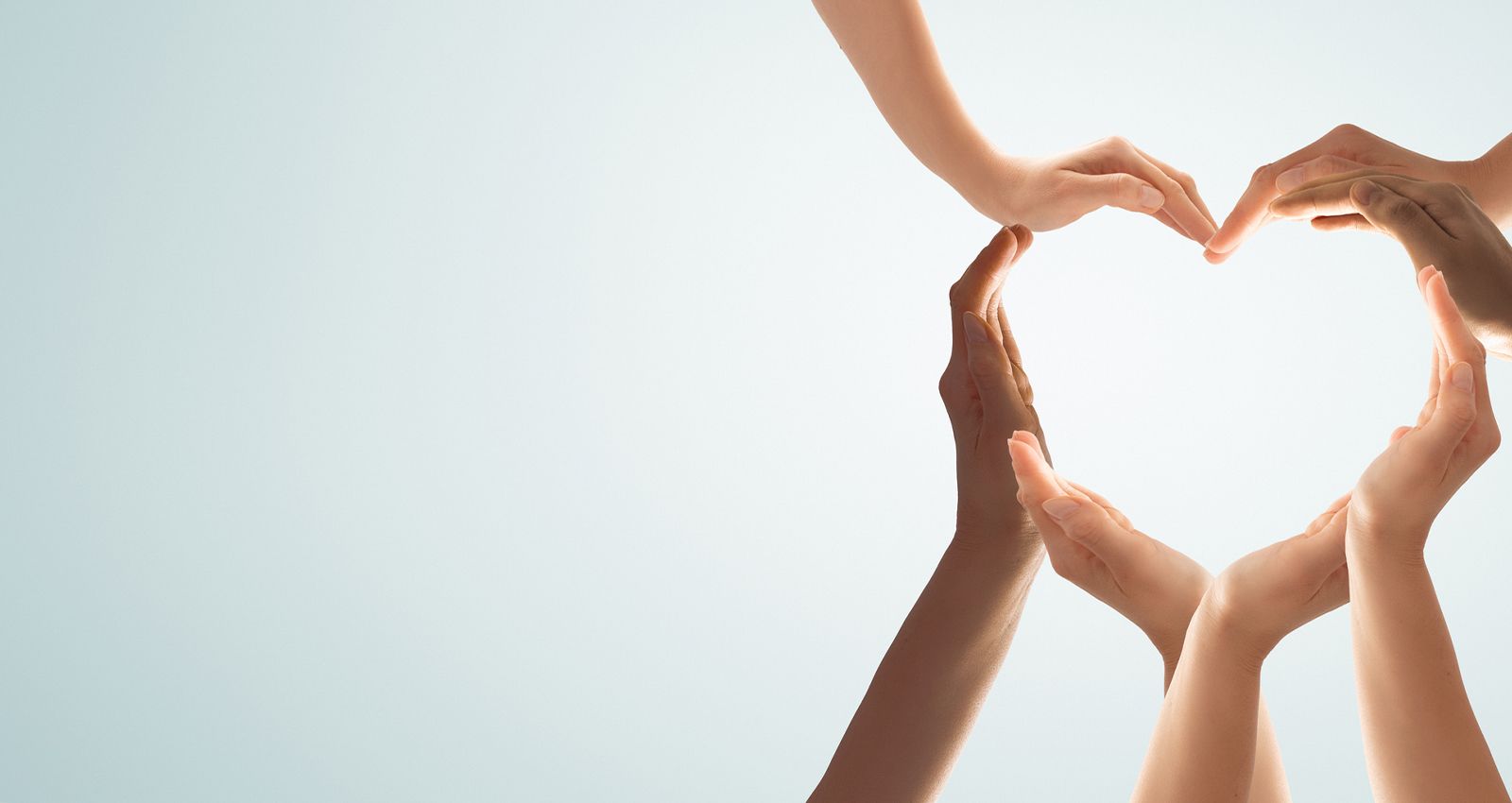 Seven hands coming together to form the shape of a heart
