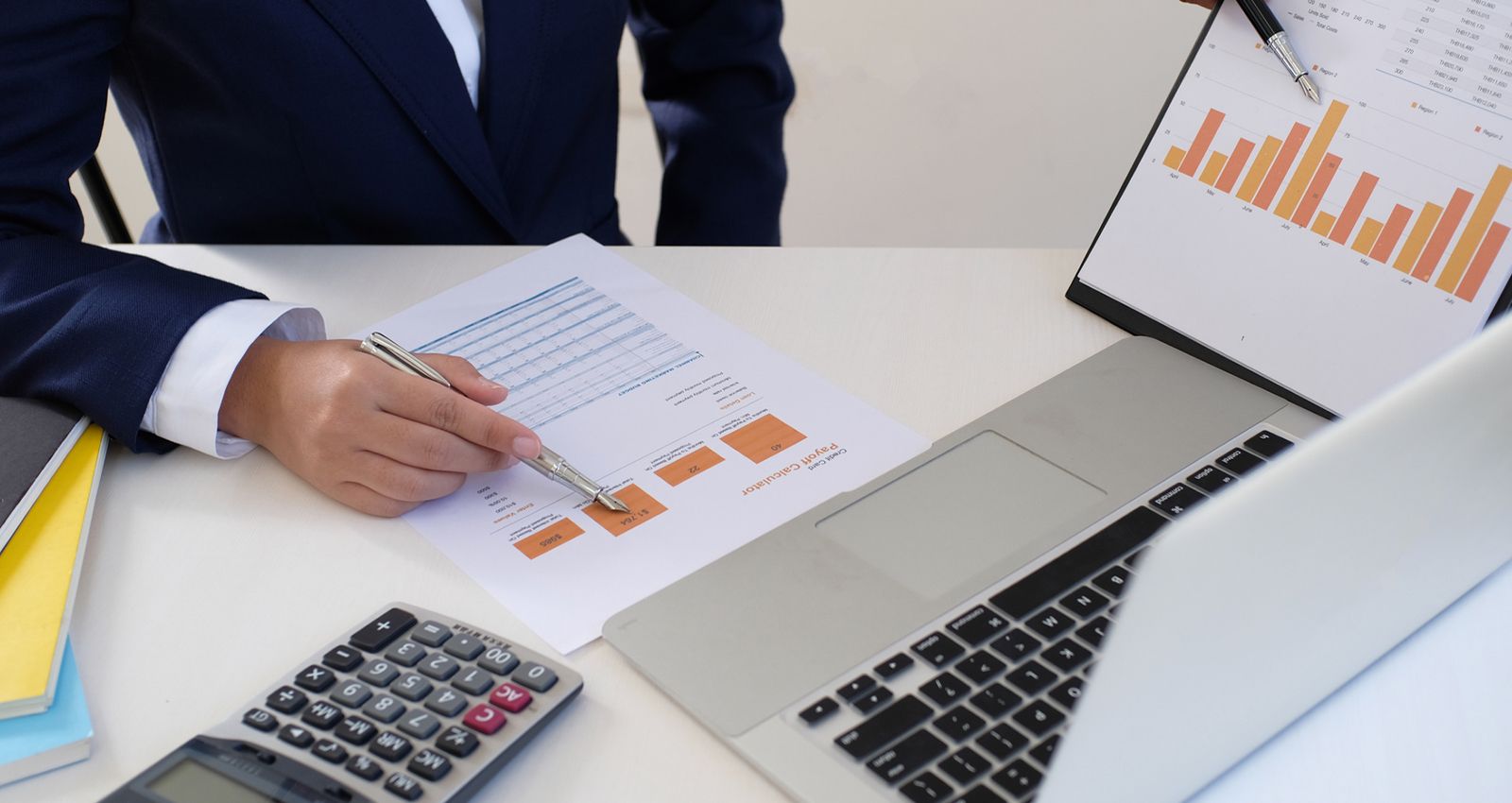 Man at a table looking through charts in front of his laptop
