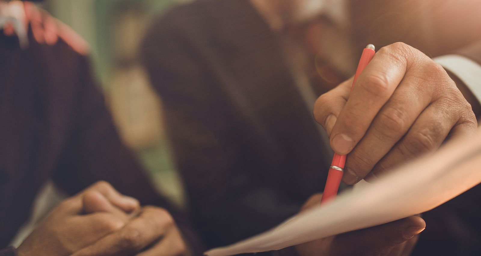 Close up of two men looking over documents while one points with a pen