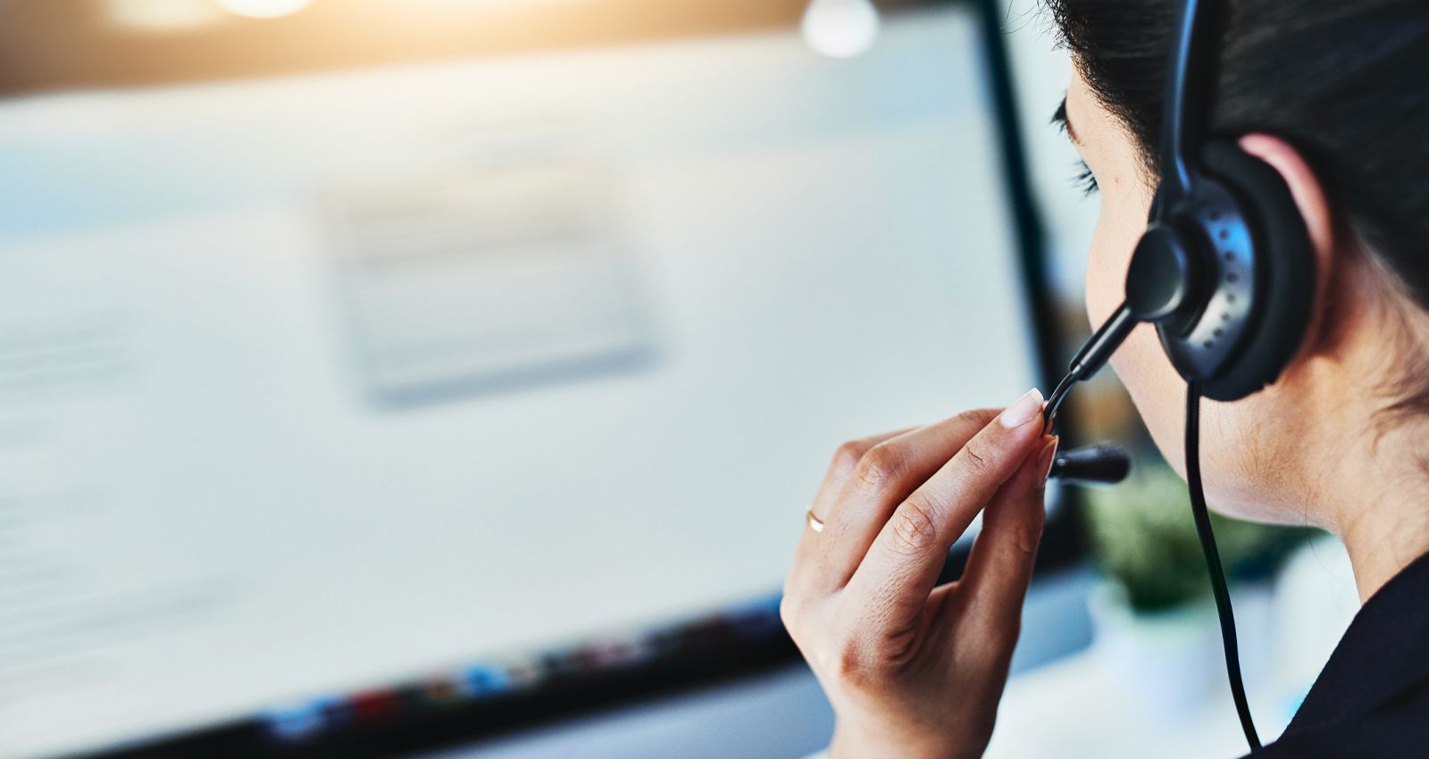 A customer service representative wearing a headset while on the phone with a customer
