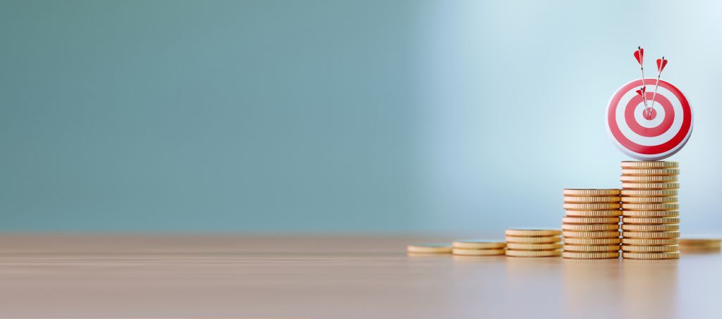 Several stacks of coins with a target and arrows on top of the tallest one