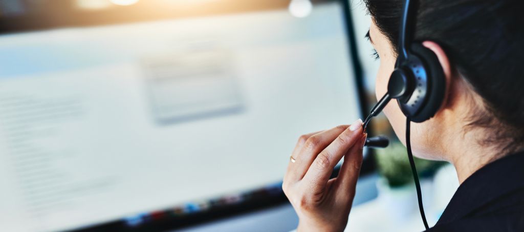 A customer service representative wearing a headset while on the phone with a customer