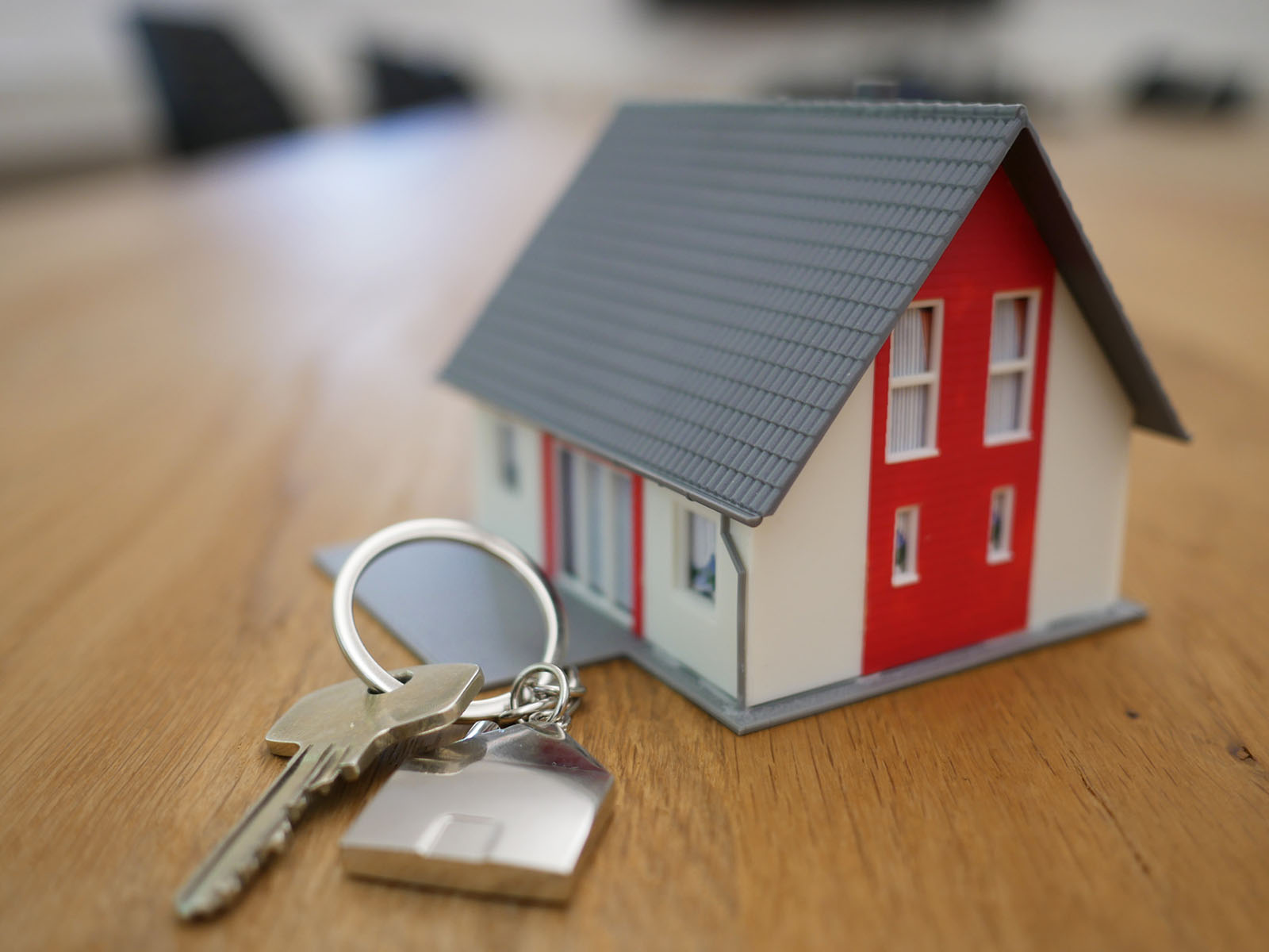 A replica house on a wooden table with a key lying next to it