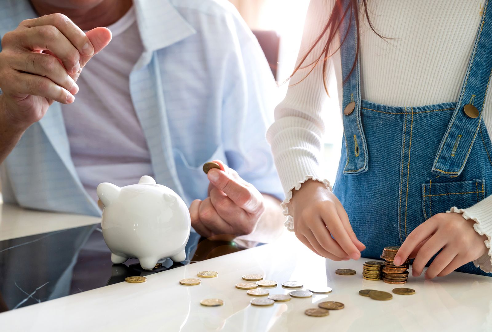 Man using a piggy bank to teach young girl how to save