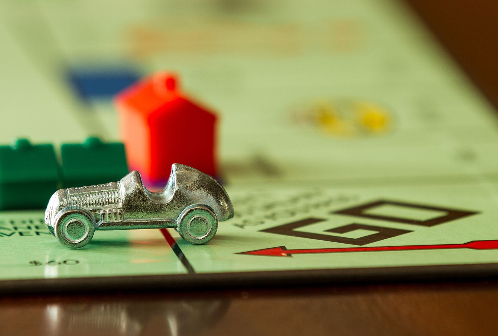 Car game piece on a Monopoly board passing Go