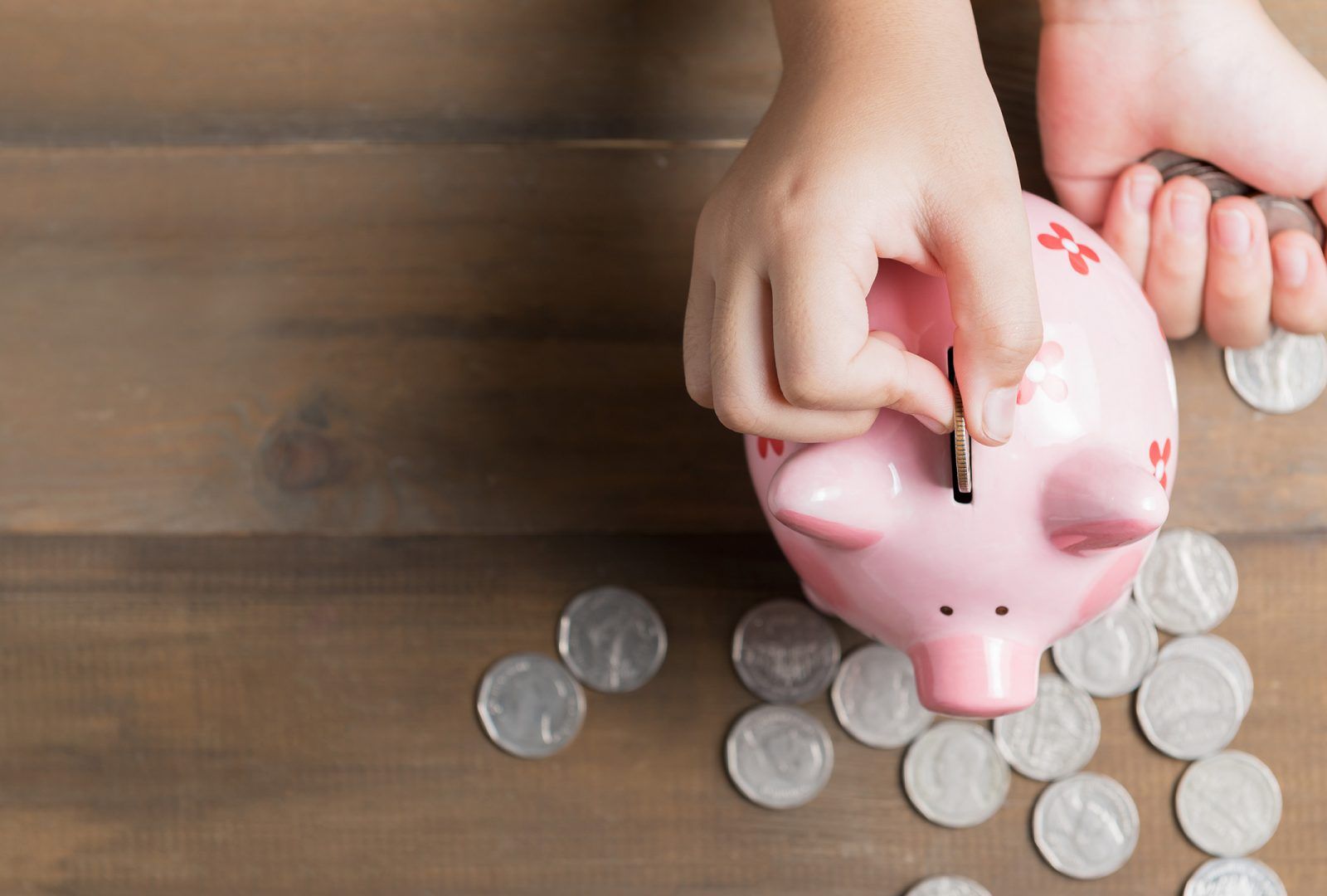 child putting coins in a piggy bank